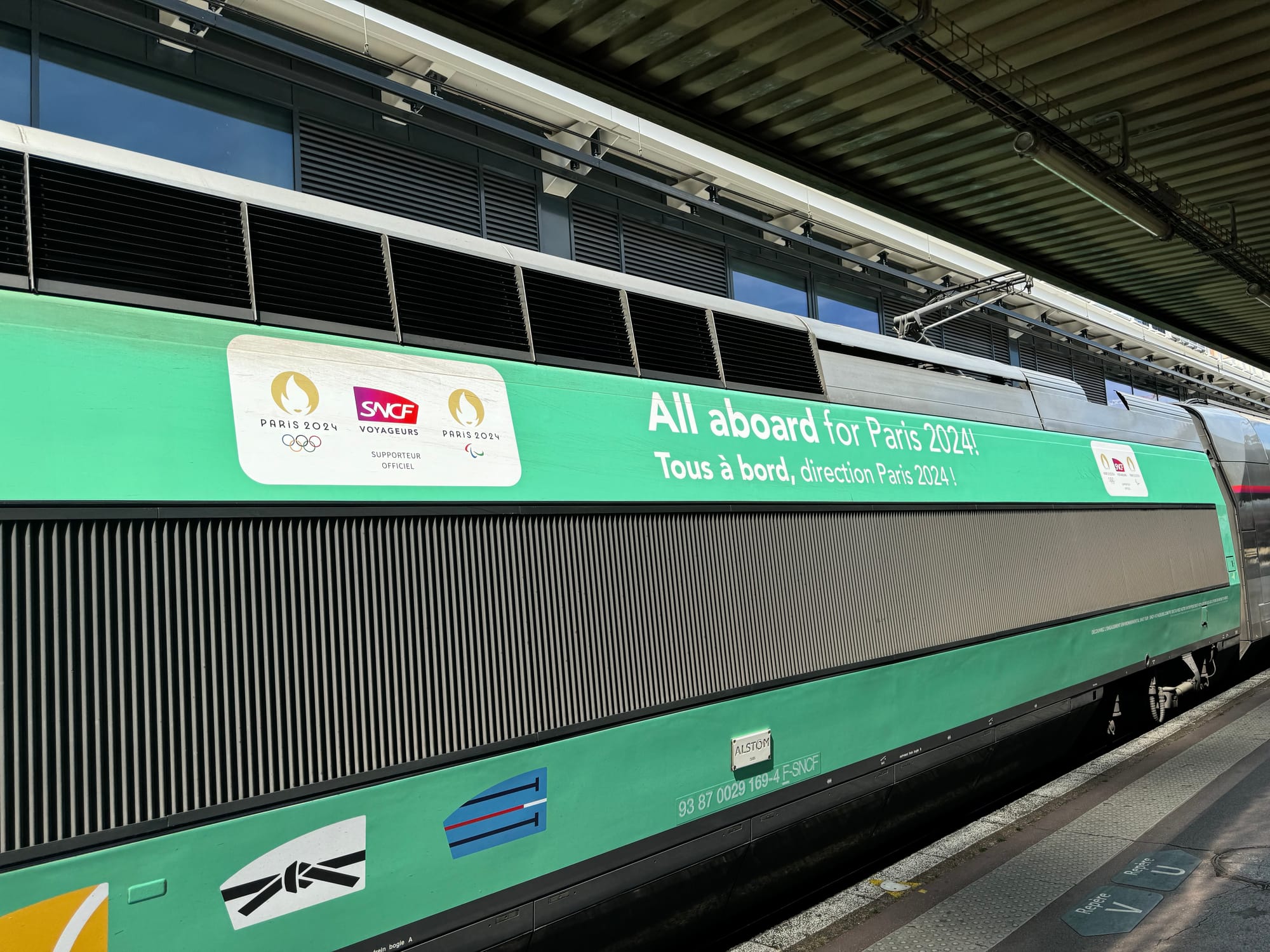 A side view of a power car of TGV Duplex set number 285 showing the Paris olympics livery with the phrase โAll aboard for Paris 3024โ printed on the side in both English and French